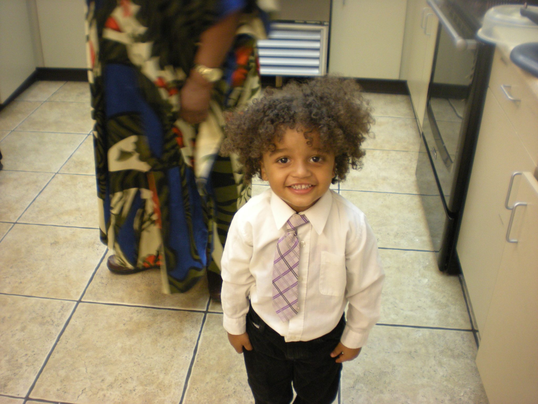 A cute little curly-headed boy smiling at the camera